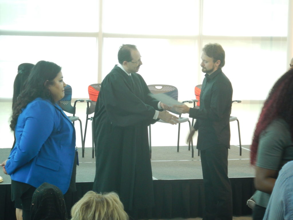 Mike, receiving his diploma from the judge at the citizenship ceremony.